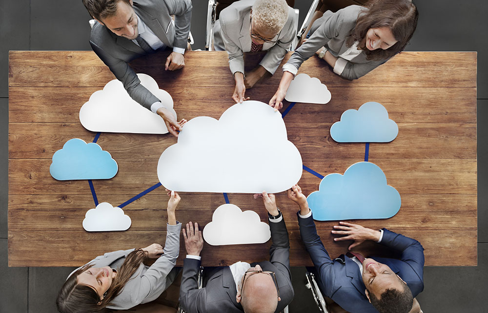 Business people sitting around the table connecting via cloud communication
