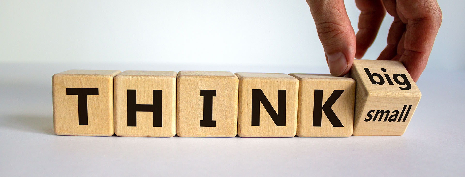 Man turning word blocks from think small to big